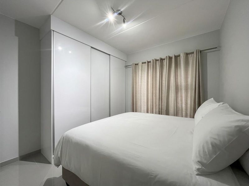 A clean and well-maintained bedroom featuring a large built-in sliding door wardrobe and neutral finishes.