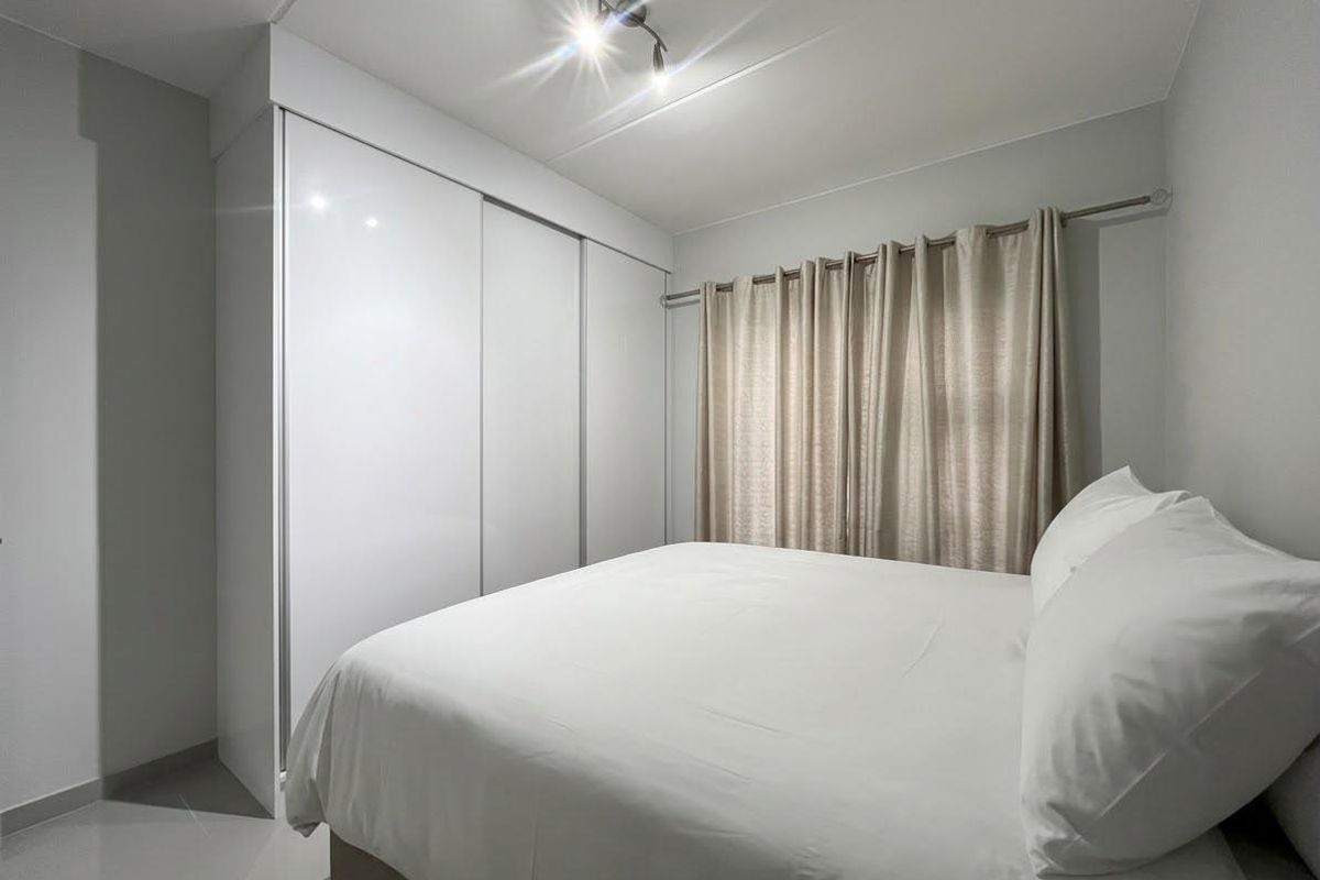 A clean and well-maintained bedroom featuring a large built-in sliding door wardrobe and neutral finishes.