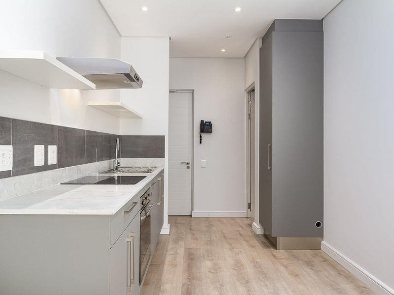 Modern kitchen featuring sleek grey cabinetry, stone countertops, integrated appliances, and high-quality laminate flooring in a clean, minimalist design.