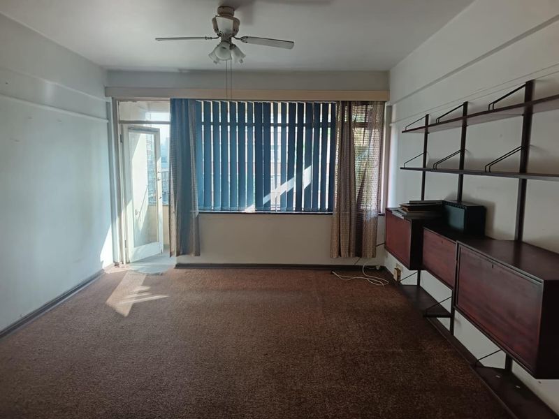 Spacious living room featuring a ceiling fan, wall-mounted shelving, and direct access to a balcony through a glass door.