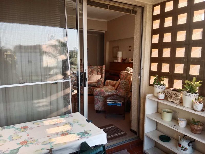 A covered balcony area featuring tiled flooring and a decorative lattice screen, providing direct access to the interior living space through sliding glass doors.