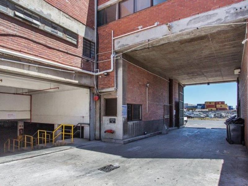 Industrial-style garage and loading area featuring exposed brickwork, concrete flooring, and access to underground parking facilities.