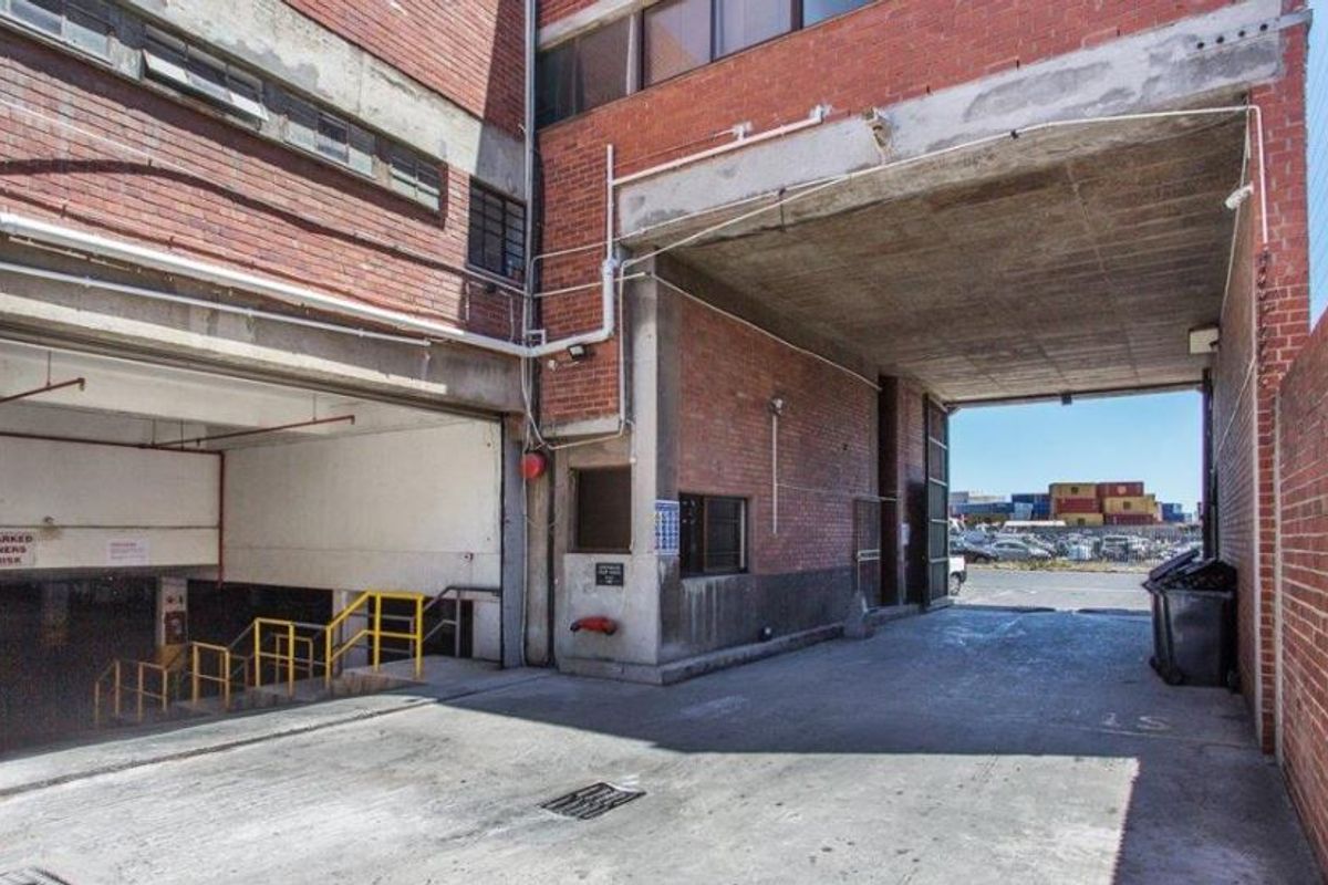 Industrial-style garage and loading area featuring exposed brickwork, concrete flooring, and access to underground parking facilities.