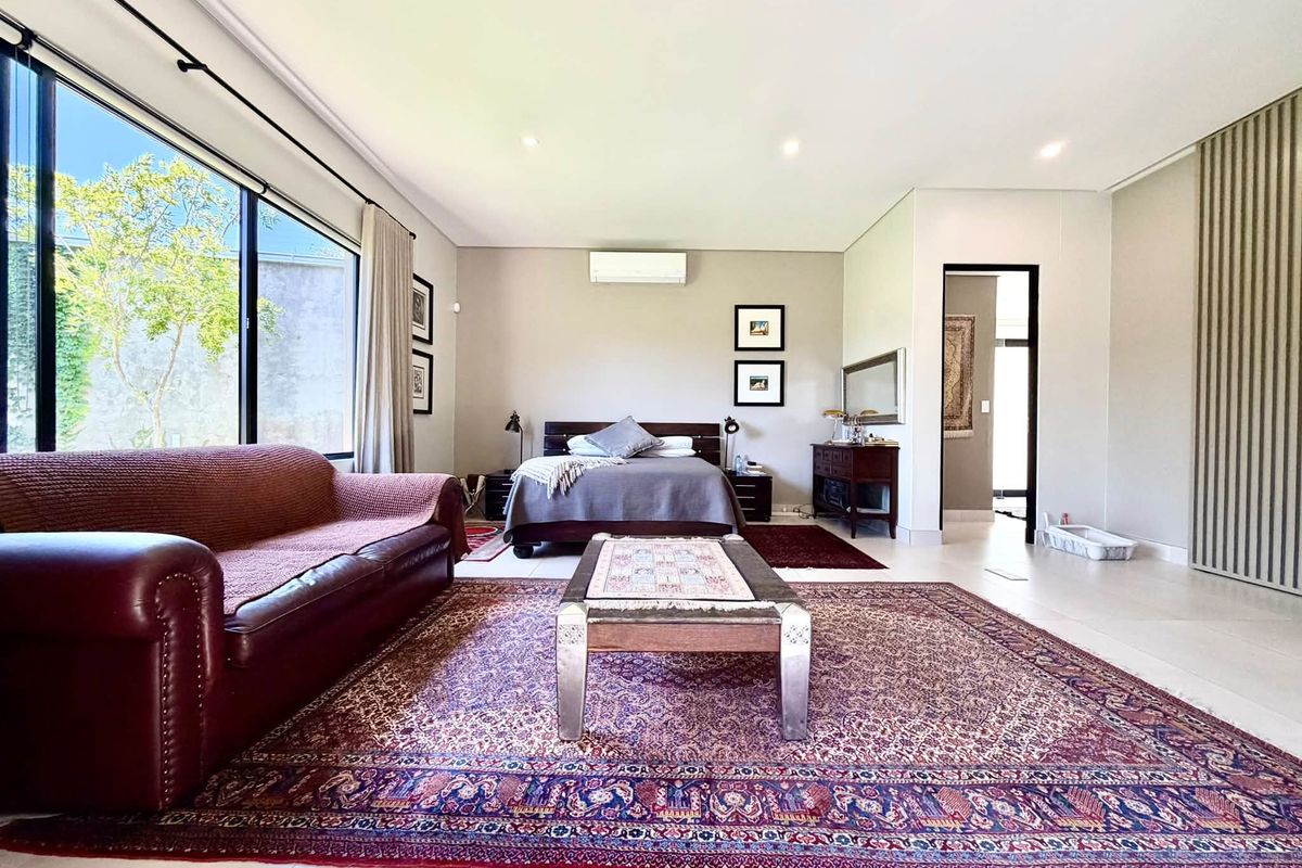 Spacious bedroom featuring large floor-to-ceiling windows, tiled flooring, and a wall-mounted air conditioning unit, offering a bright and comfortable living space.