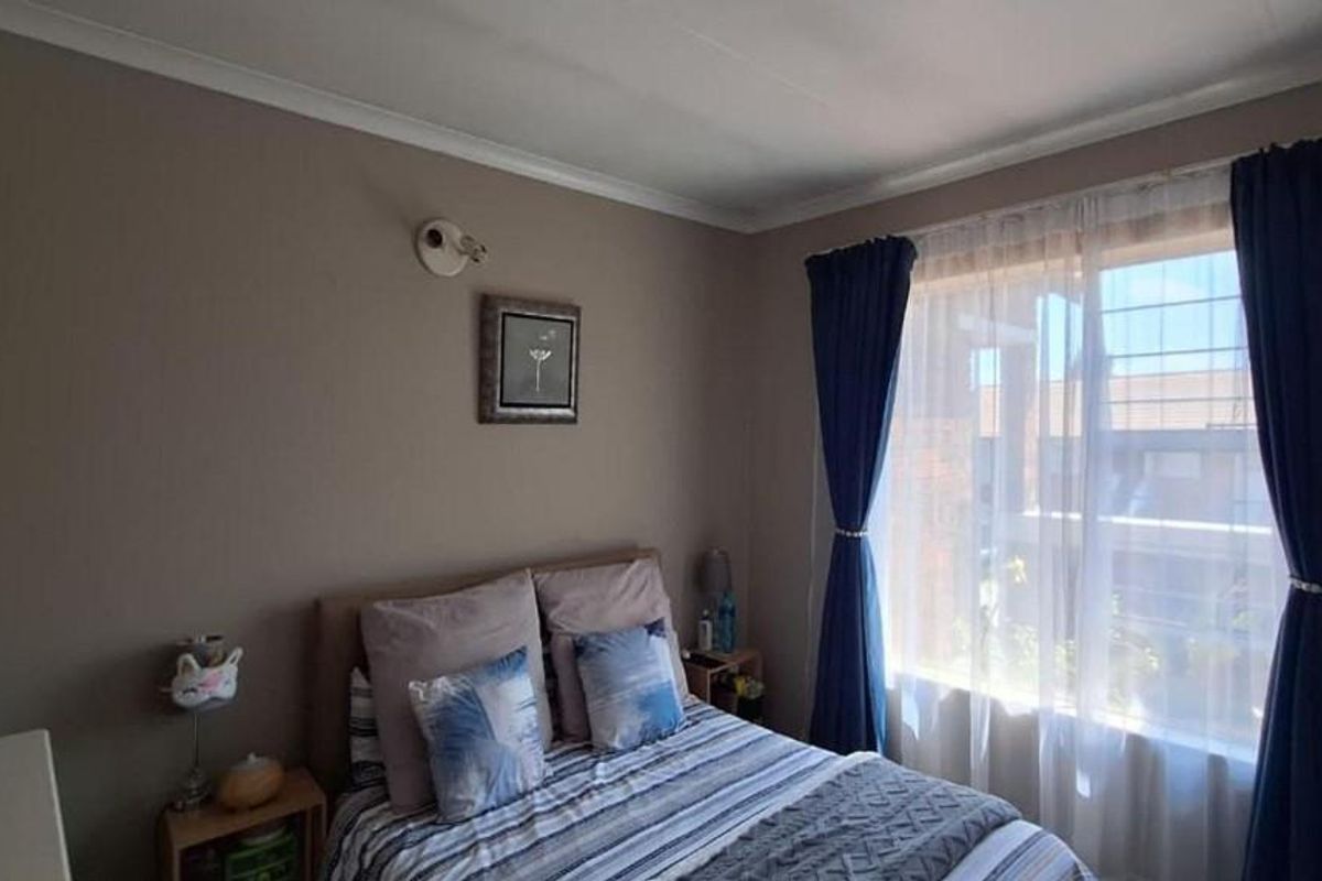 A cozy bedroom featuring neutral wall tones, a large window with natural light, and classic coving detail.