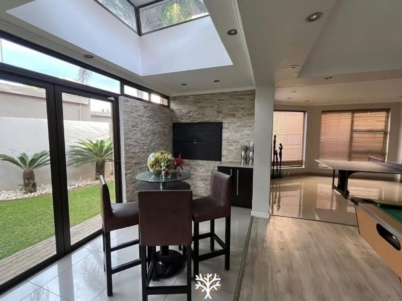 Spacious open-plan living area featuring a large skylight, stone feature wall with built-in fireplace, and seamless transition to the garden through aluminium sliding doors.