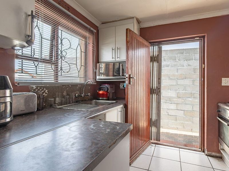 Compact kitchen featuring built-in cabinetry, laminate countertops, a gas hob, and an integrated oven, with direct access to an exterior courtyard area.