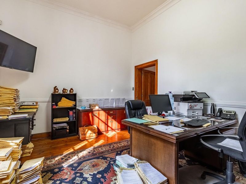 A functional office space featuring polished timber flooring, classic crown molding, and traditional wooden door frames, providing a professional work environment.