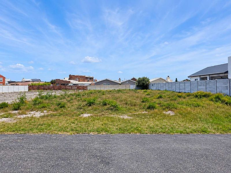 A vacant residential plot featuring level ground, established boundary walls, and direct street access in a developed neighbourhood.