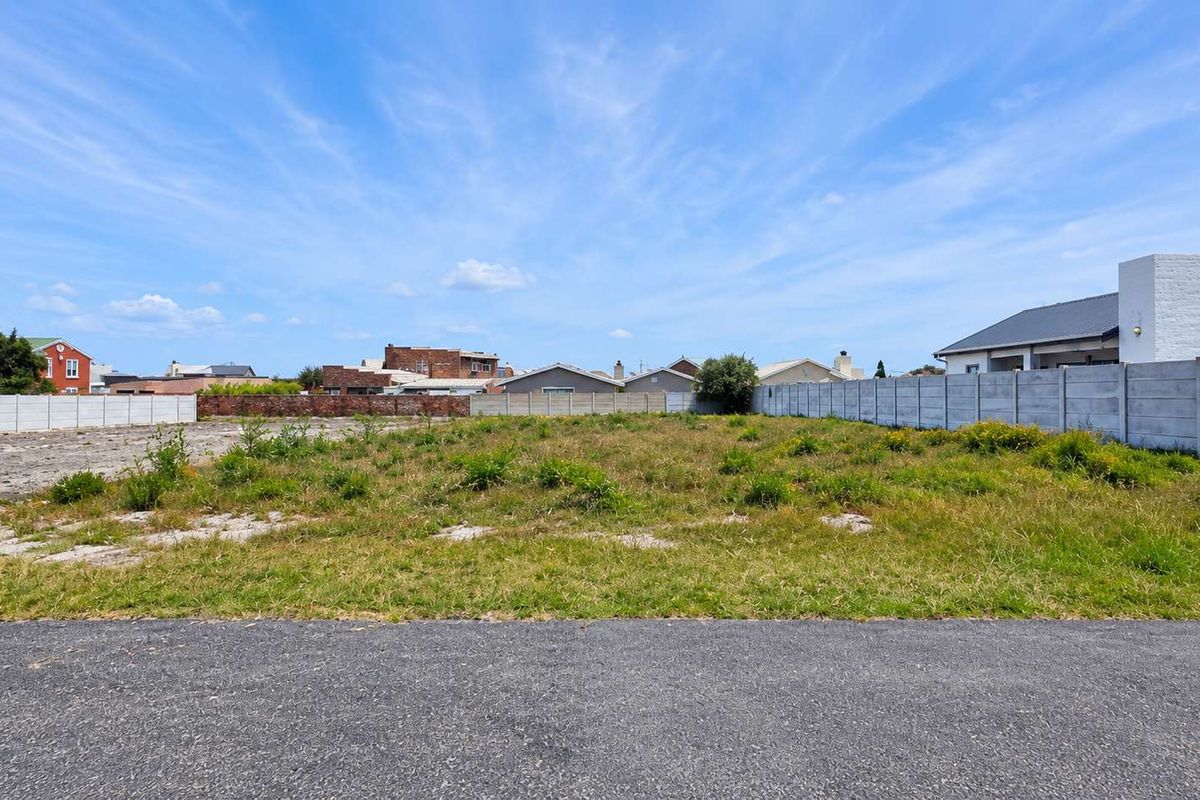 A vacant residential plot featuring level ground, established boundary walls, and direct street access in a developed neighbourhood.