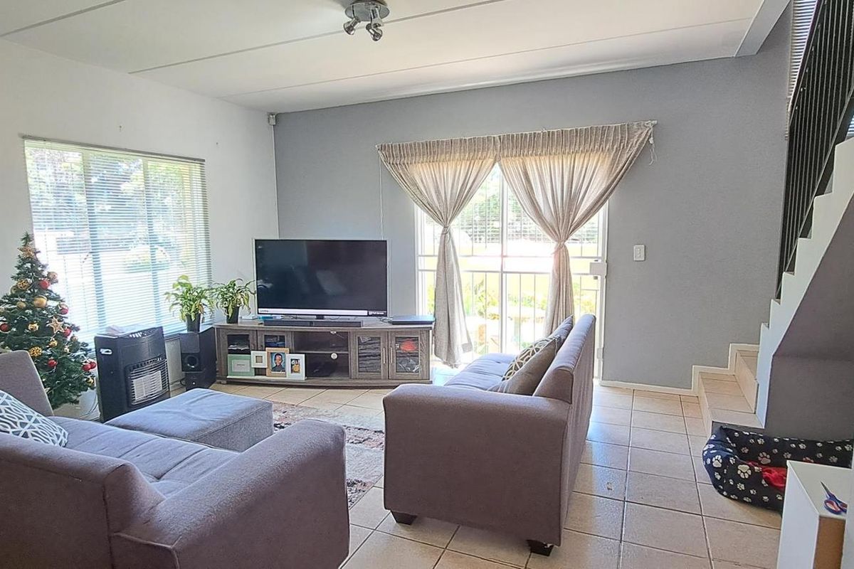 Spacious living room featuring tiled flooring, a staircase with a metal railing, and a sliding glass door providing access to the exterior.