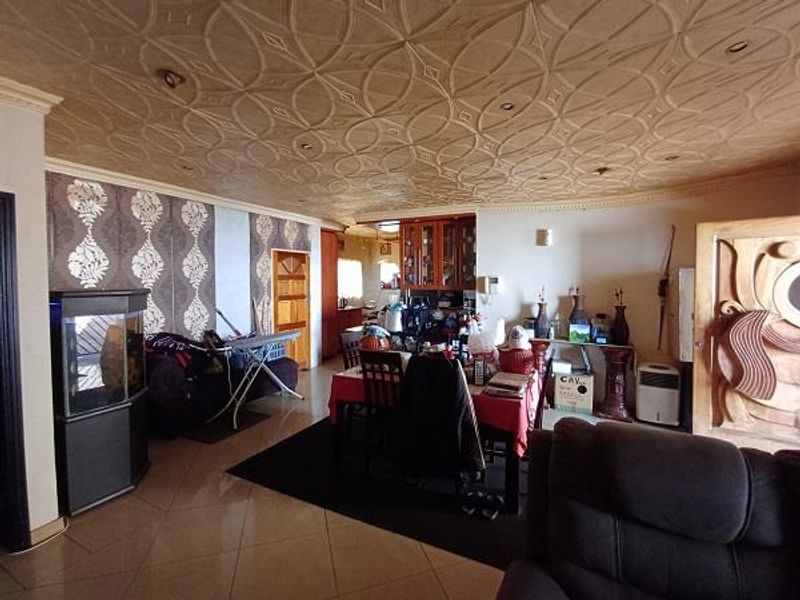Spacious open-plan living and dining area featuring a unique decorative patterned ceiling, recessed lighting, and tiled flooring throughout.
