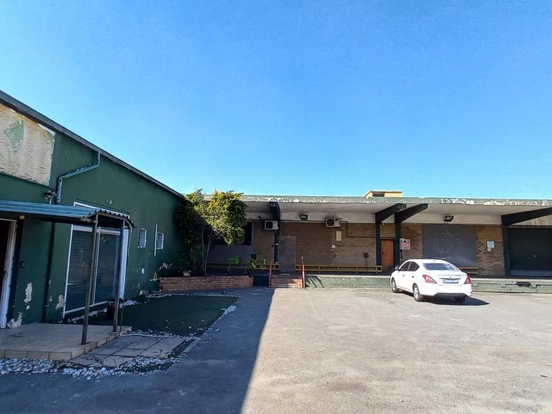 Exterior view of an industrial property featuring loading bays, roller shutter doors, and a paved yard area.