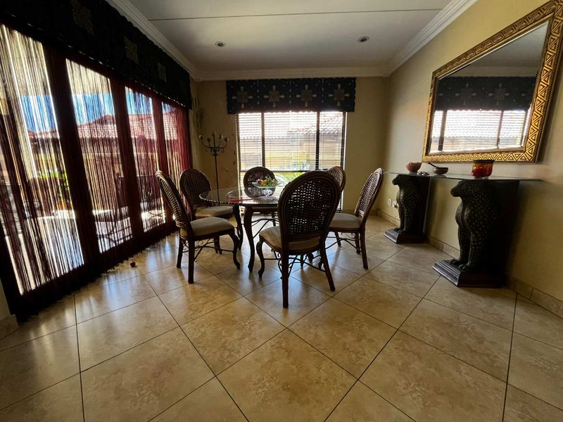 A dining room featuring tiled flooring, crown molding, and large sliding glass doors providing natural light, though some wall water damage is visible.