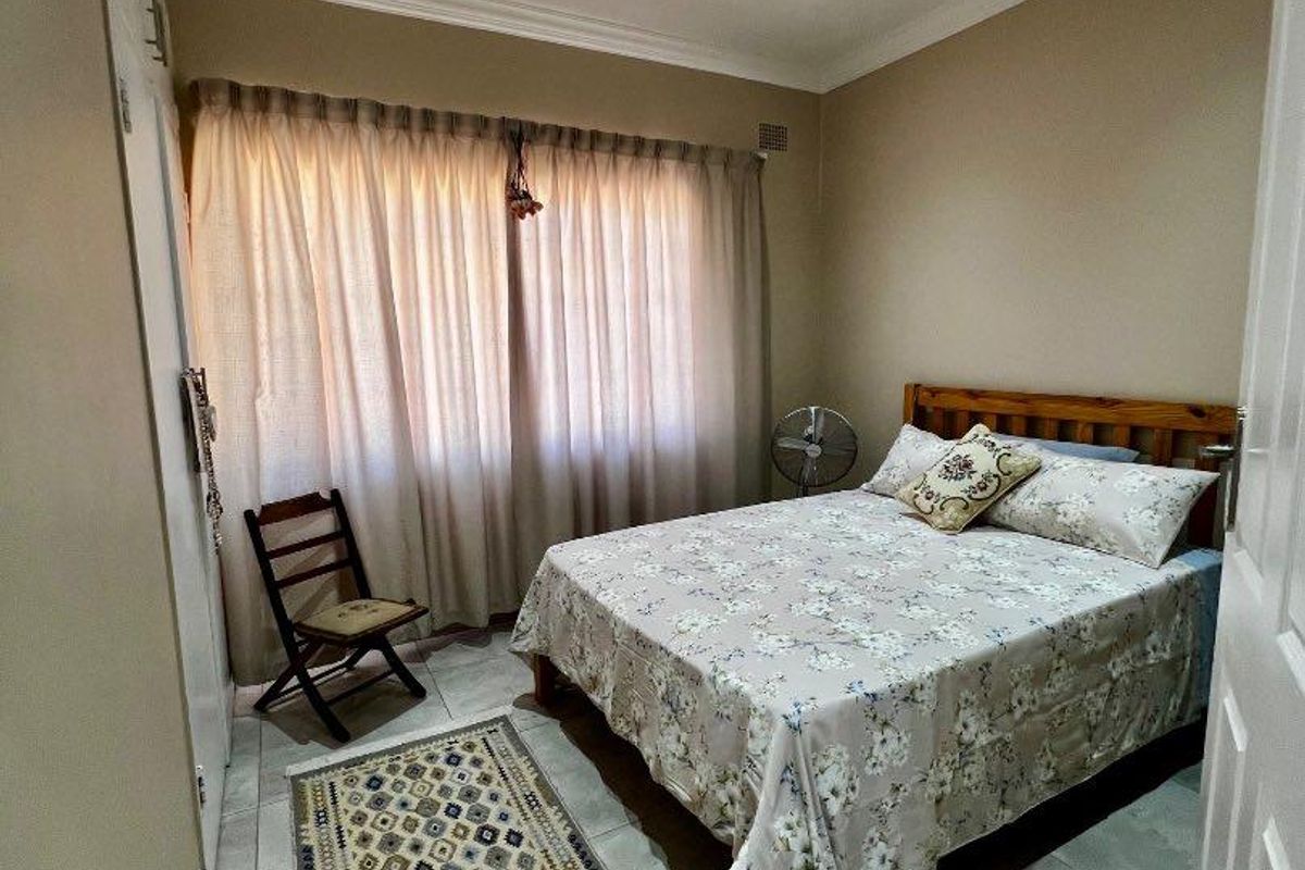 A well-maintained bedroom featuring tiled flooring, built-in cupboards, and recessed ceiling lighting.