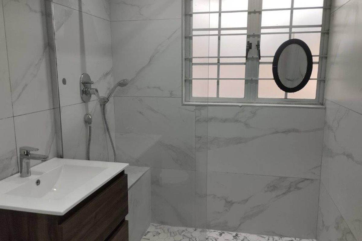 Modern bathroom featuring marble-look wall tiles, hexagonal floor tiles, a floating vanity cabinet, and a glass-enclosed shower area with a security window grille.