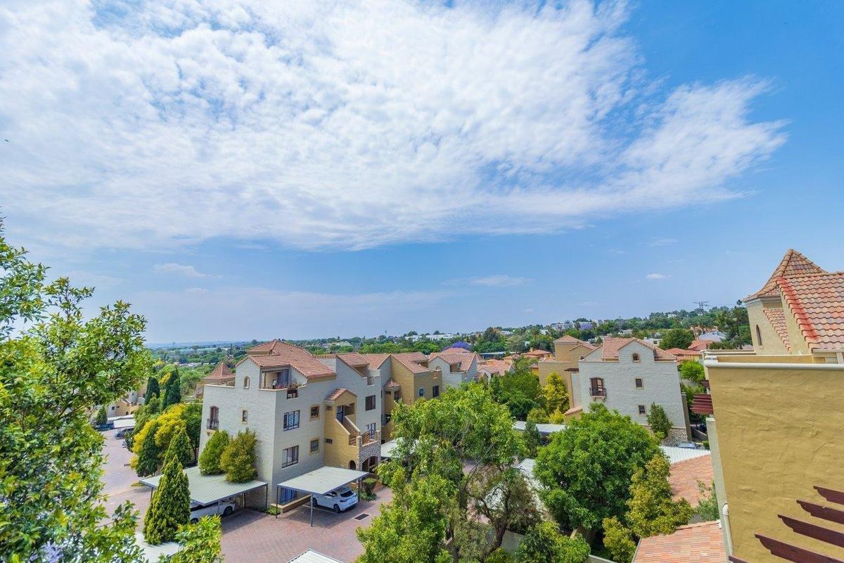 An elevated aerial view of the apartment complex, showcasing the surrounding neighborhood, tiled roof architecture, paved driveways, and established green landscaping.