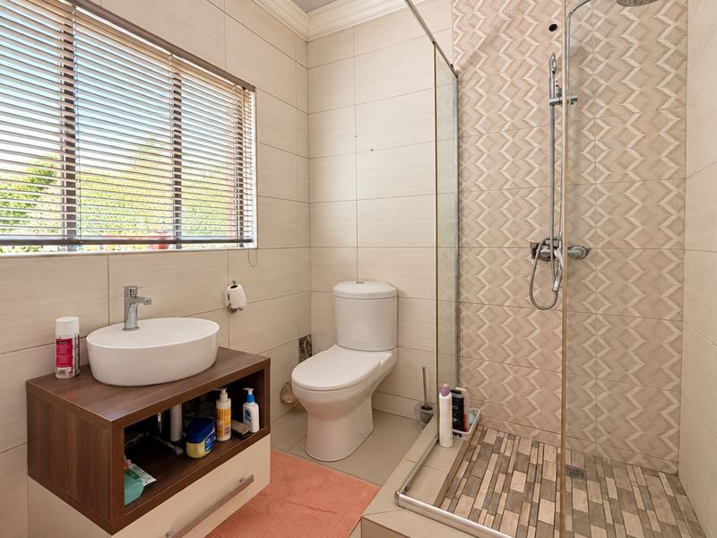 Modern bathroom featuring a vessel sink with vanity, a toilet, and a walk-in shower with decorative tiled accents and a glass screen.