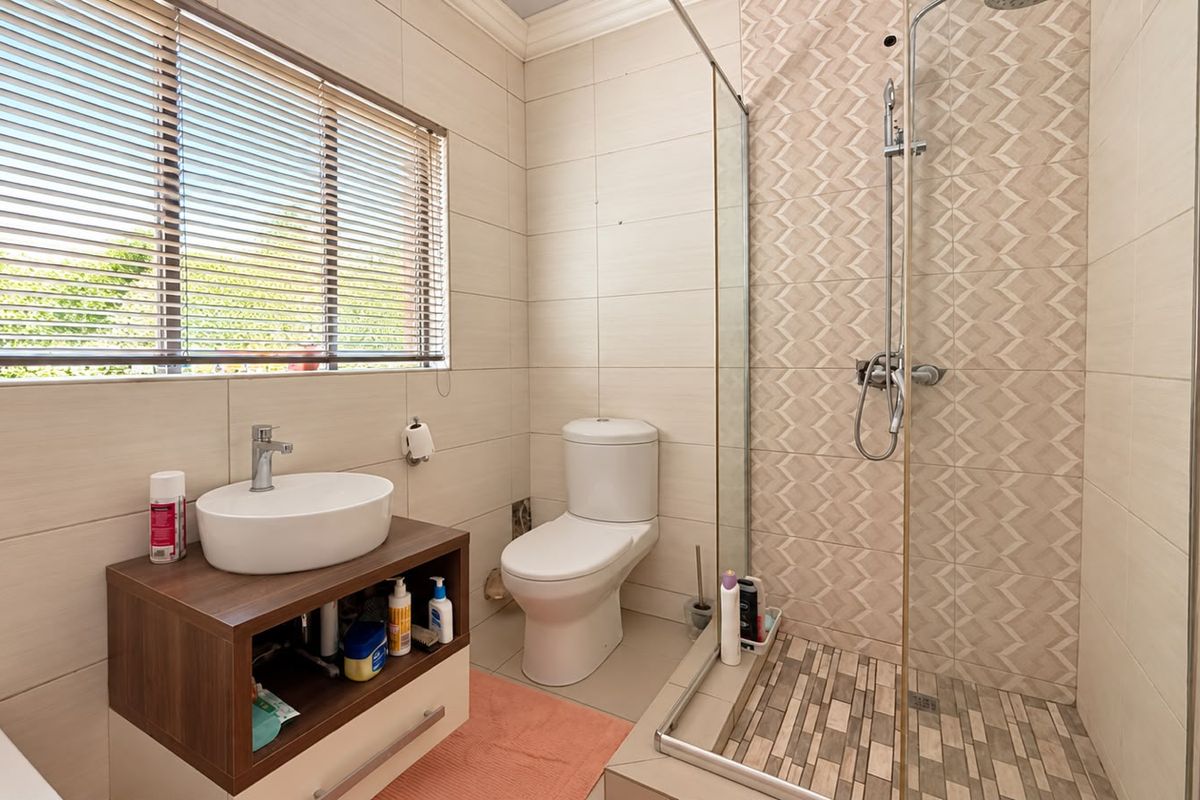 Modern bathroom featuring a vessel sink with vanity, a toilet, and a walk-in shower with decorative tiled accents and a glass screen.