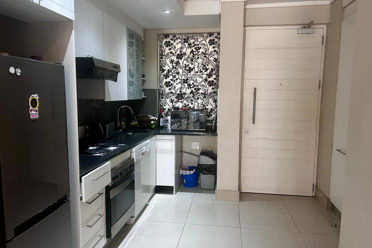 Compact modern kitchen featuring granite countertops, built-in cabinetry, integrated appliances, and tiled flooring, providing a functional and efficient culinary workspace.