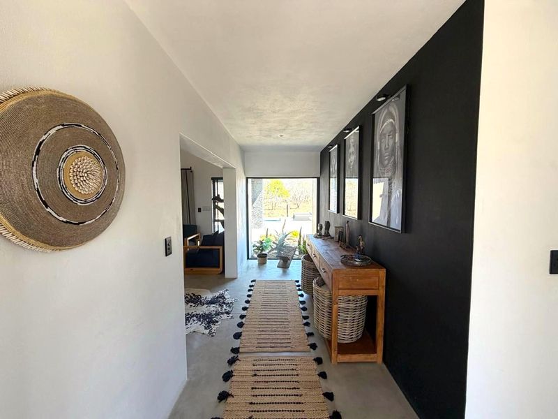 A bright, modern hallway featuring polished concrete floors, a striking black accent wall, and a clear view through to the outdoor area.