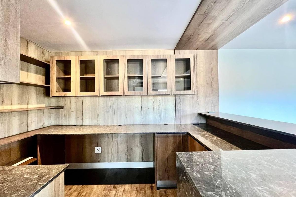 A modern kitchen featuring wood-grain cabinetry, stone countertops, and a breakfast bar, offering a clean and functional workspace.