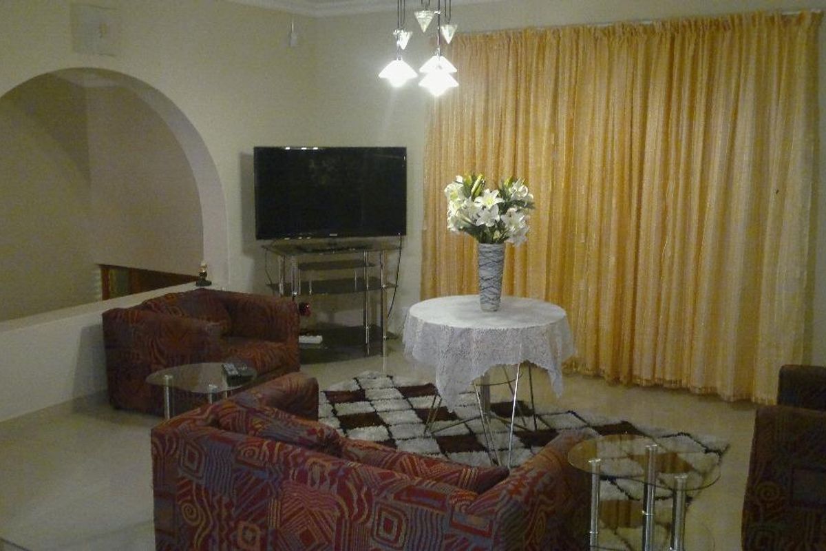 A living room featuring tiled flooring, a decorative arched wall opening, and a multi-pendant light fixture.