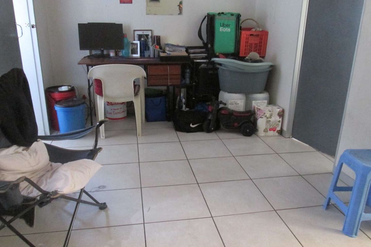 A living area featuring ceramic floor tiles, currently utilized as a multi-purpose storage and workspace area.