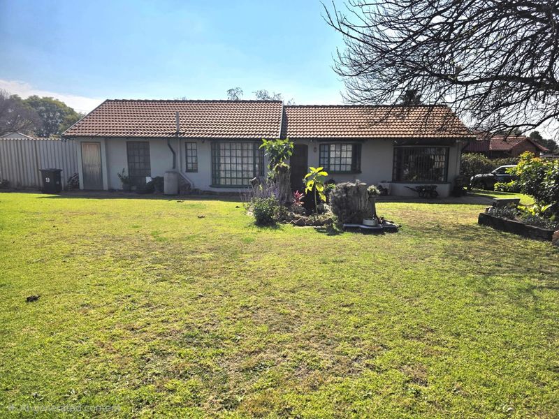 A single-story residential property featuring a tiled roof, security-barred windows, and a spacious front garden area.