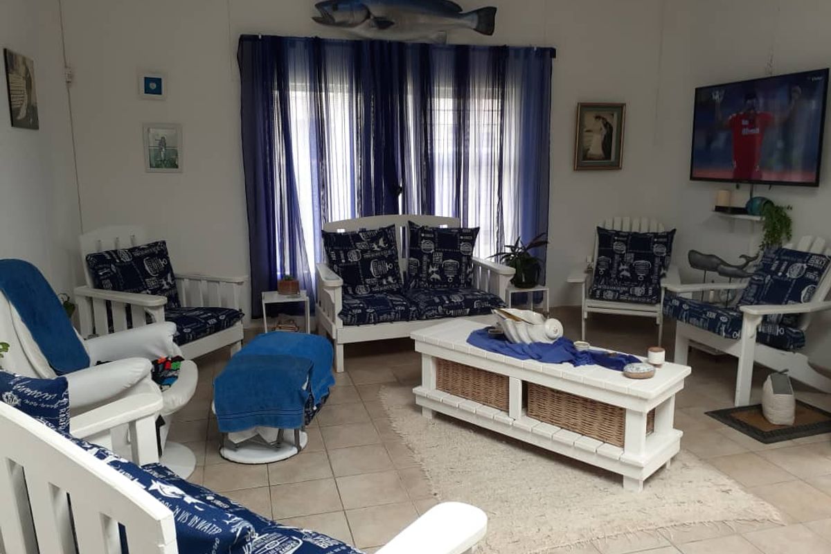 A living room featuring tiled flooring and large windows with curtains, providing a functional space for relaxation.