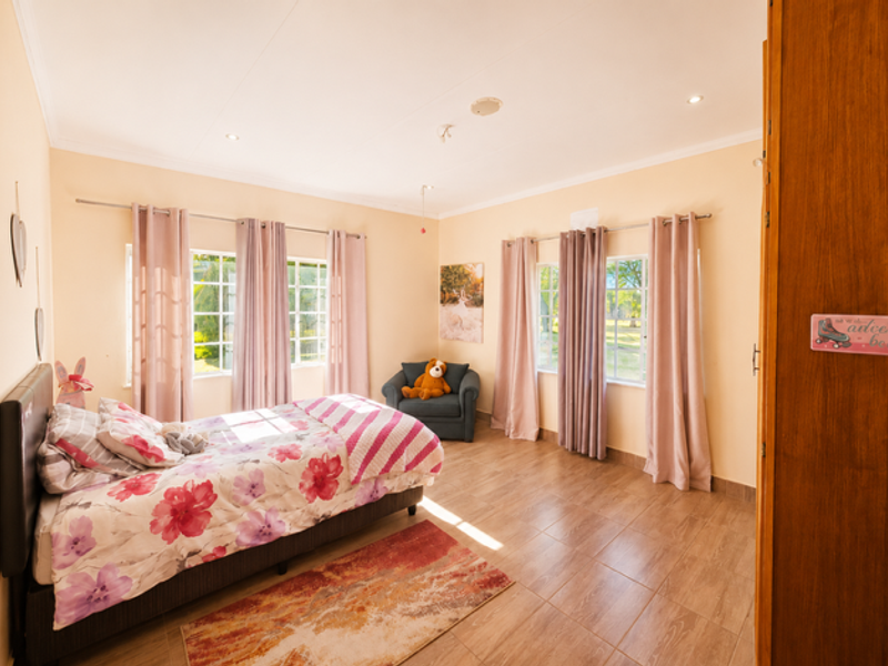 A bright and spacious bedroom featuring tiled flooring, recessed downlighting, and large windows that allow for ample natural light.