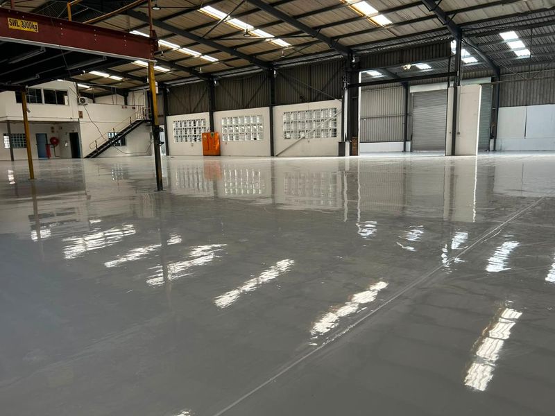 Spacious industrial warehouse featuring a high-gloss epoxy floor, steel portal frame construction, overhead crane, and large roller shutter access.