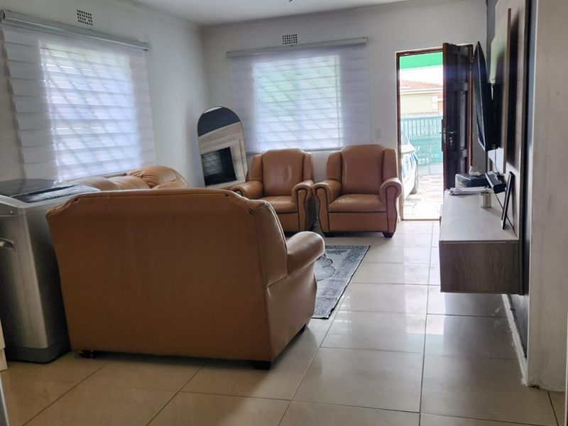 A living room featuring tiled flooring, roller blinds, and a wall-mounted floating media console, with direct access to the exterior.