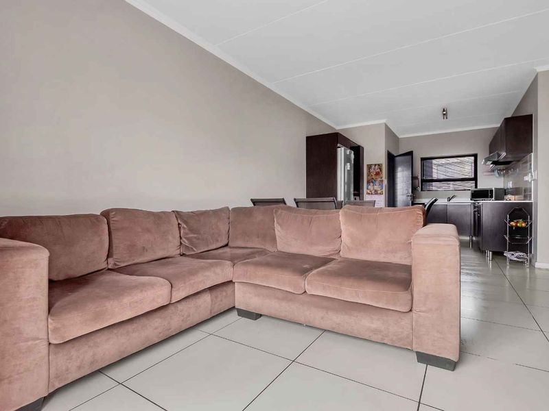 Open-plan living area featuring tiled flooring and a modern kitchen with built-in cabinetry and integrated appliances.