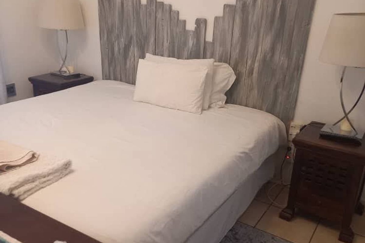 A bedroom featuring tiled flooring and a rustic wooden headboard, providing a neutral base for potential interior design updates.