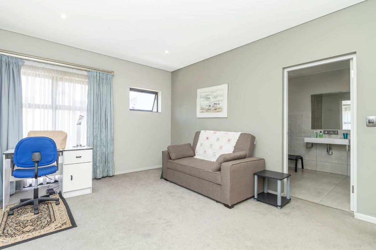 A well-maintained bedroom featuring neutral wall tones, carpeted flooring, and an en-suite bathroom with modern fixtures.