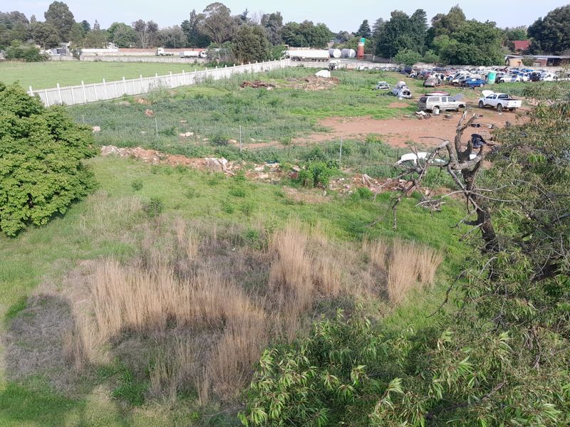 Aerial view of a large, undeveloped plot of land featuring perimeter fencing and boundary walls, currently showing signs of neglect and overgrown vegetation.