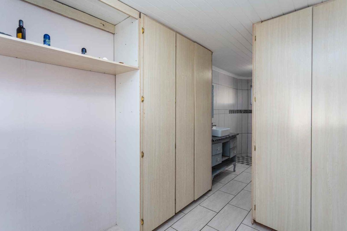A functional dressing area featuring extensive built-in cabinetry and tiled flooring, leading directly into an adjoining bathroom space.