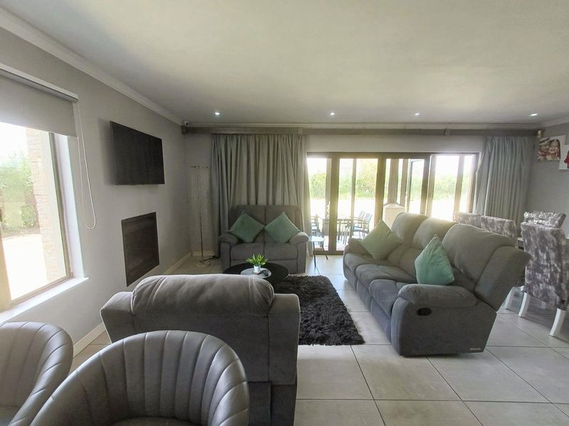 Spacious open-plan living area featuring tiled floors, recessed lighting, a built-in fireplace, and large sliding glass doors providing access to the outdoor area.