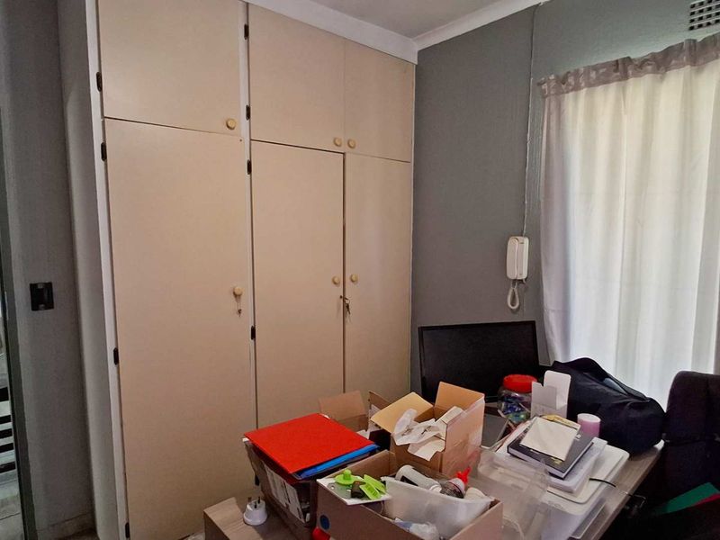 A bedroom featuring built-in cupboards, neutral wall finishes, and a view into the hallway.
