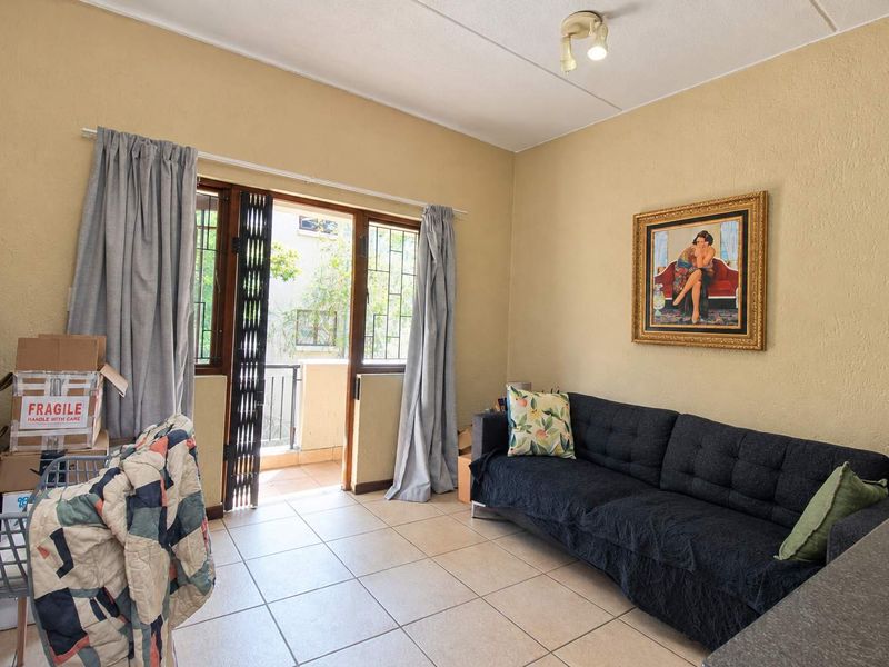 A living room featuring tiled flooring and a sliding glass door providing access to a balcony, with neutral wall finishes.