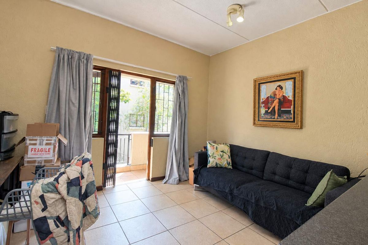 A living room featuring tiled flooring and a sliding glass door providing access to a balcony, with neutral wall finishes.