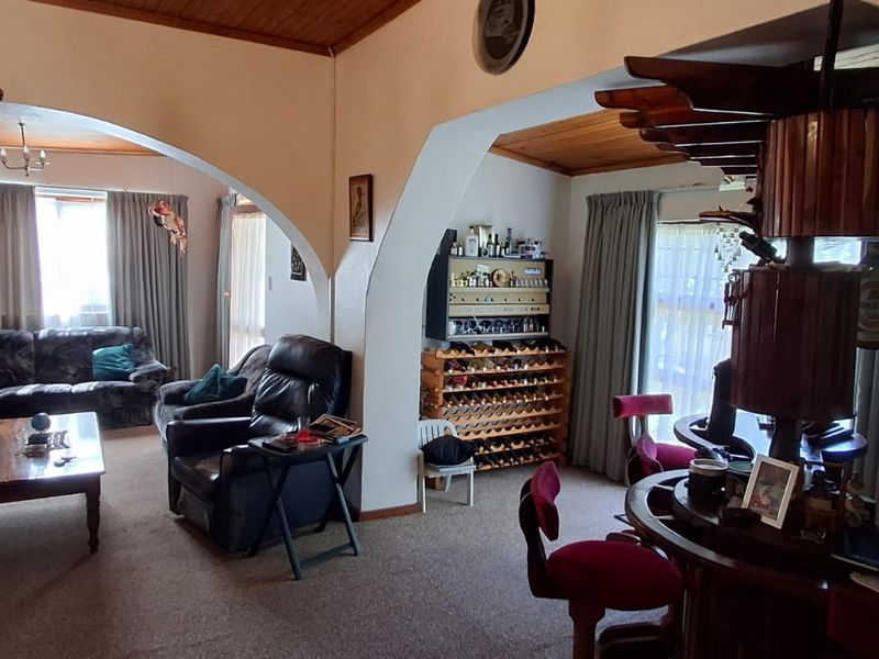 Spacious living area featuring distinctive arched room dividers, a timber-paneled ceiling, and a built-in bar area, offering a traditional layout with potential for modernization.