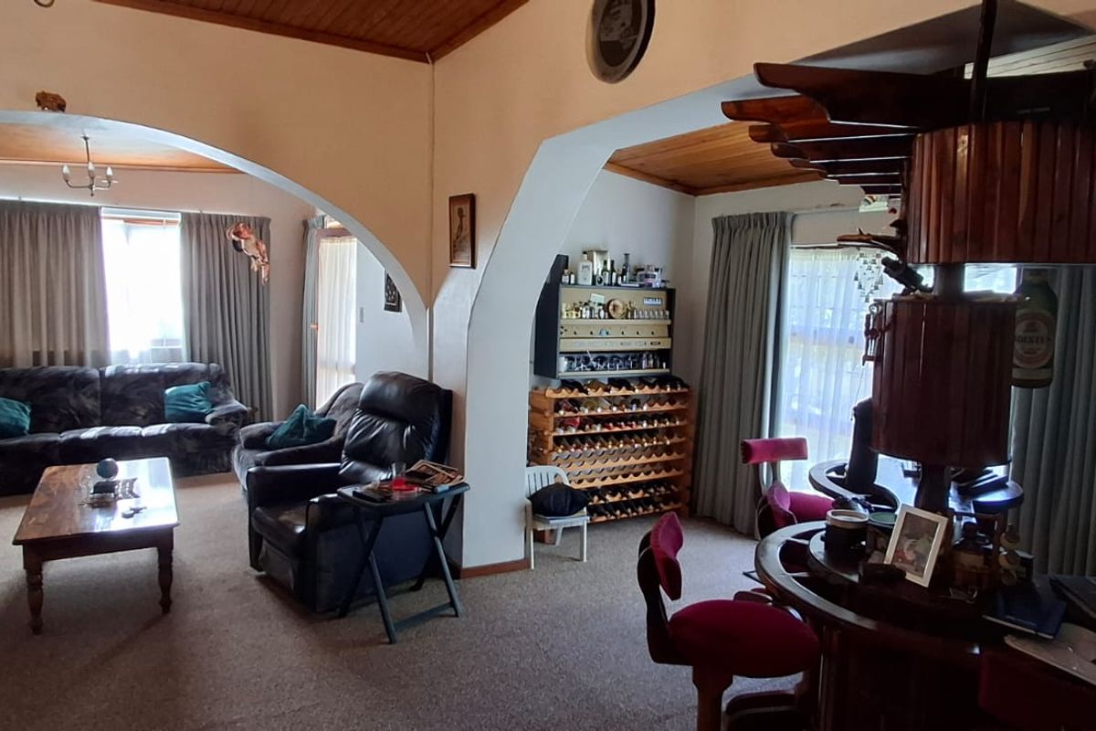 Spacious living area featuring distinctive arched room dividers, a timber-paneled ceiling, and a built-in bar area, offering a traditional layout with potential for modernization.