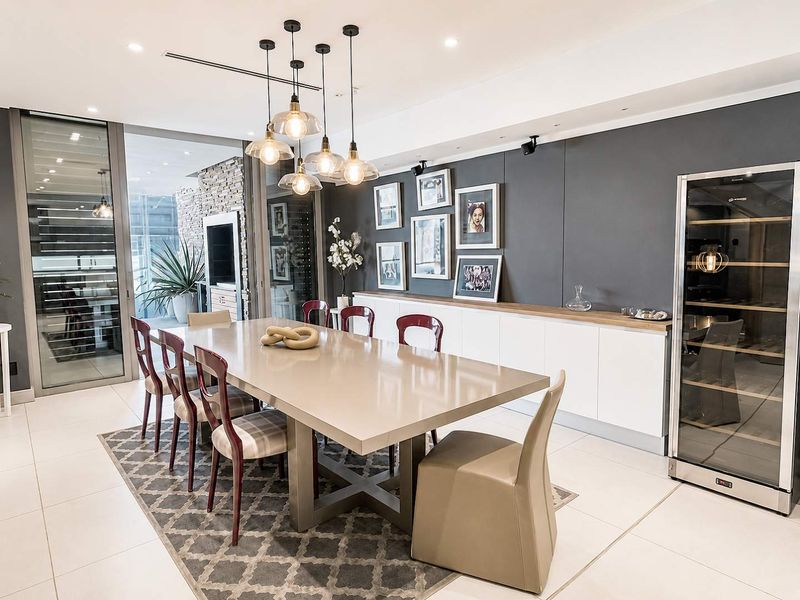 Modern dining room featuring sleek built-in cabinetry, an integrated wine cooler, recessed lighting, and large sliding glass doors leading to an outdoor patio area.