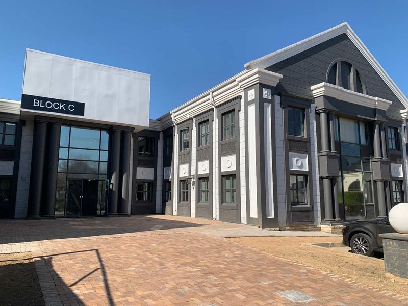 Front exterior view of Block C office building featuring a modern glass entrance, decorative architectural columns, and a paved driveway.