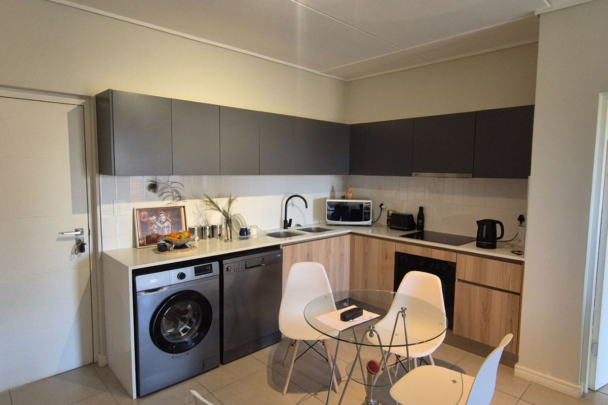 Modern kitchen featuring sleek grey and wood-tone cabinetry, integrated appliances, tiled backsplash, and a functional layout with ample storage space.