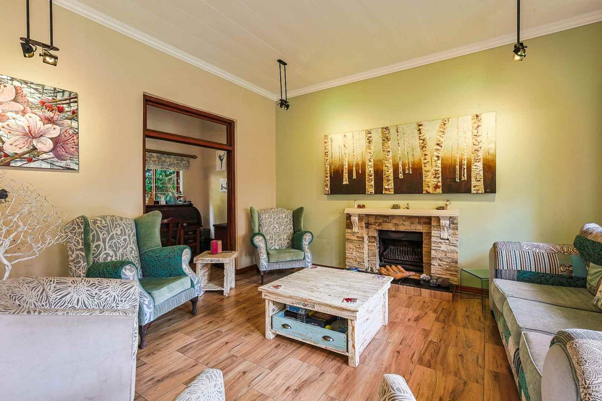 A cozy living room featuring a stone-clad fireplace, wood-look flooring, and crown molding, providing a warm and inviting atmosphere.