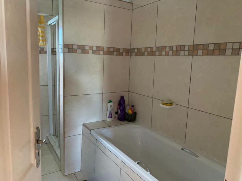 A functional bathroom featuring a built-in bathtub and a separate shower enclosure with neutral wall tiling.