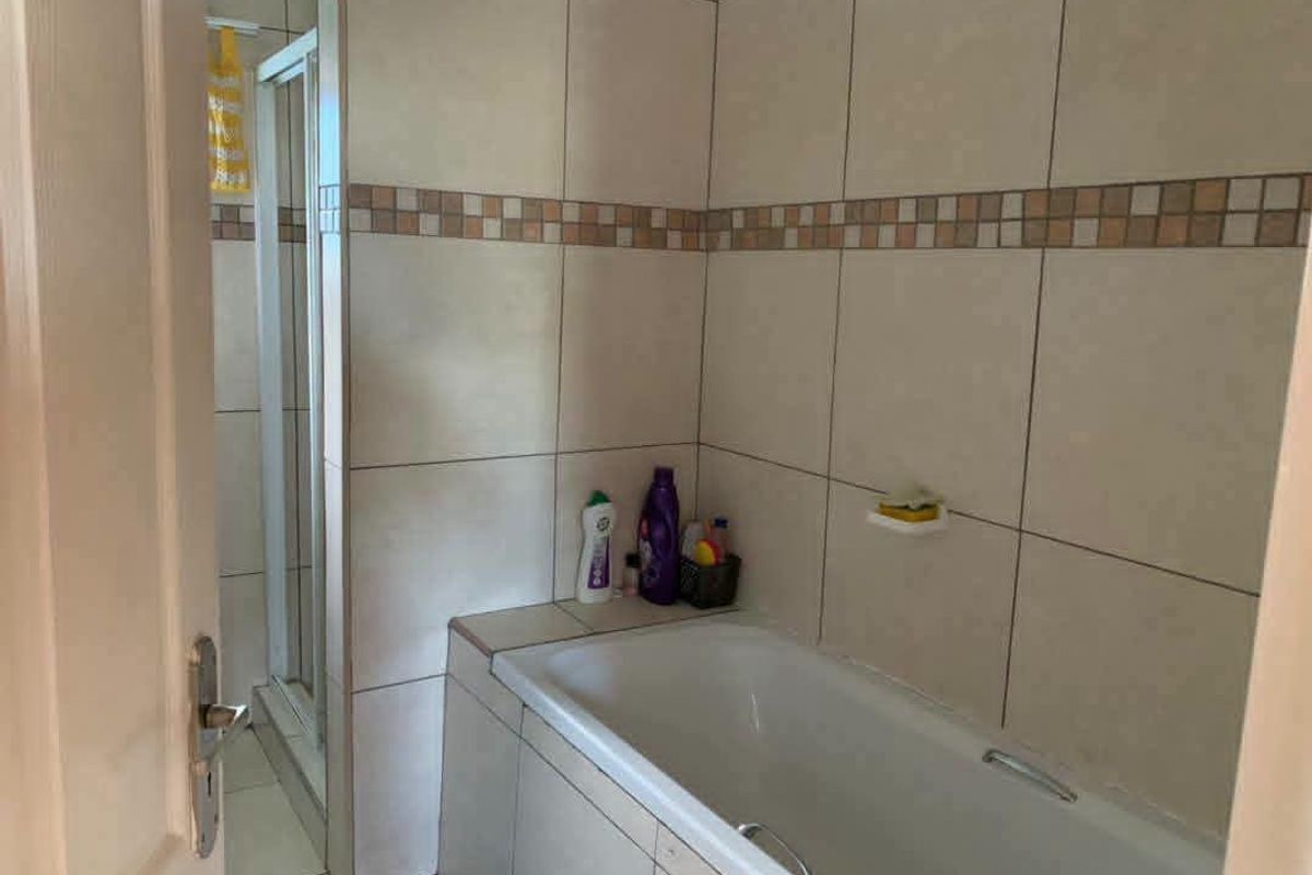 A functional bathroom featuring a built-in bathtub and a separate shower enclosure with neutral wall tiling.